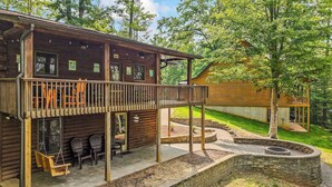 A wooden cabin with a deck, outdoor seating, and a fire pit.