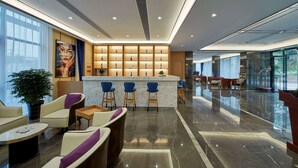Un hall d’entrée moderne doté d’un bar, de coins salon et d’une grande fenêtre.