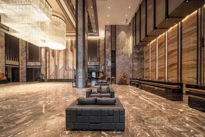 Um hall amplo com uma grande área de estar, piso de mármore e um lustre moderno.