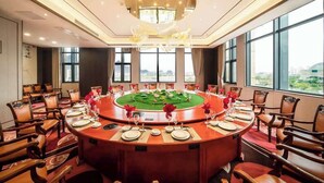 A conference room with a round table, chairs, and a decorative centerpiece. - Ramada Plaza by Wyndham Hezhou North (Hezhou)