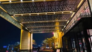A hotel entrance with a starry ceiling, palm trees, and a red carpet leading to the entrance. - Ramada Plaza by Wyndham Hezhou North (Hezhou)