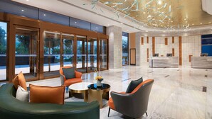 Eine geräumige Lobby mit moderner Möblierung, einem Empfangsbereich und großen Fenstern mit Blick ins Freie.
