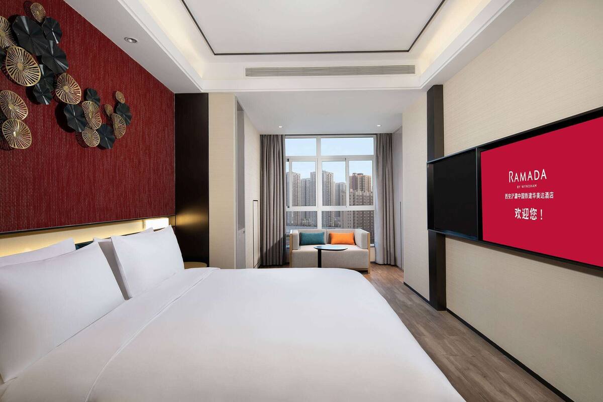Een moderne hotelkamer met een groot bed, een bank, een televisie en uitzicht op de stad.