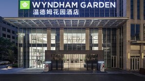 A modern hotel entrance with a glass facade, a prominent sign reading "WYNDHAM GARDEN," and a well-lit entrance area. - Wyndham Garden Wuhan Hankou (Wuhan)