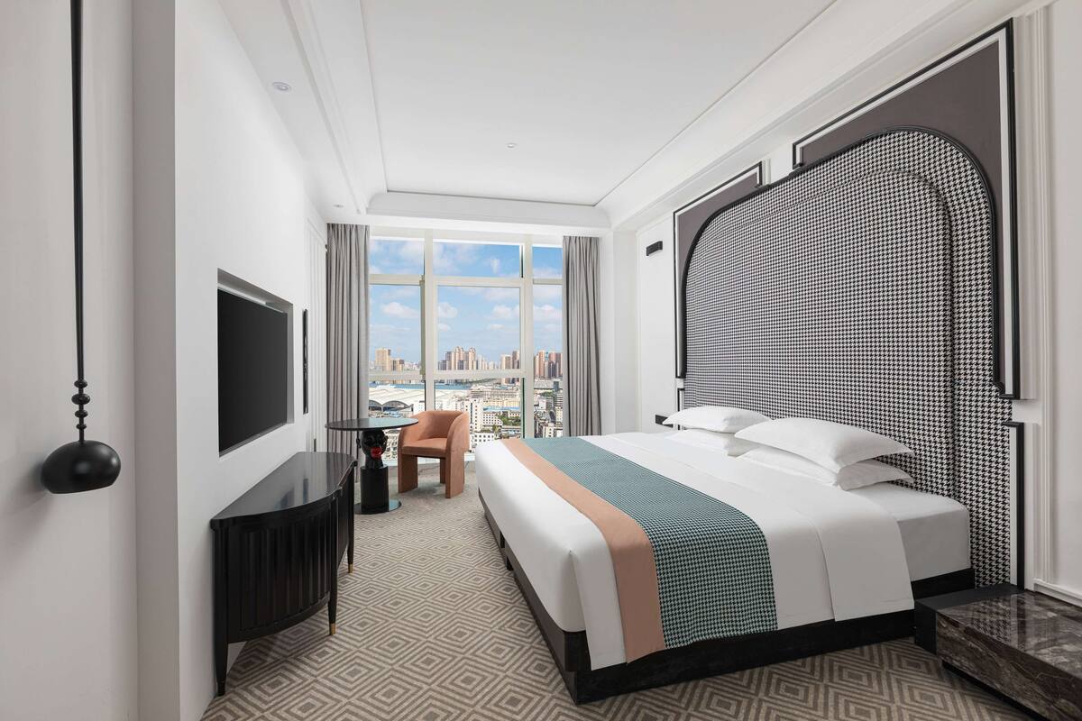 Une chambre d’hôtel avec un grand lit, une télévision, un bureau et une vue sur la ville.