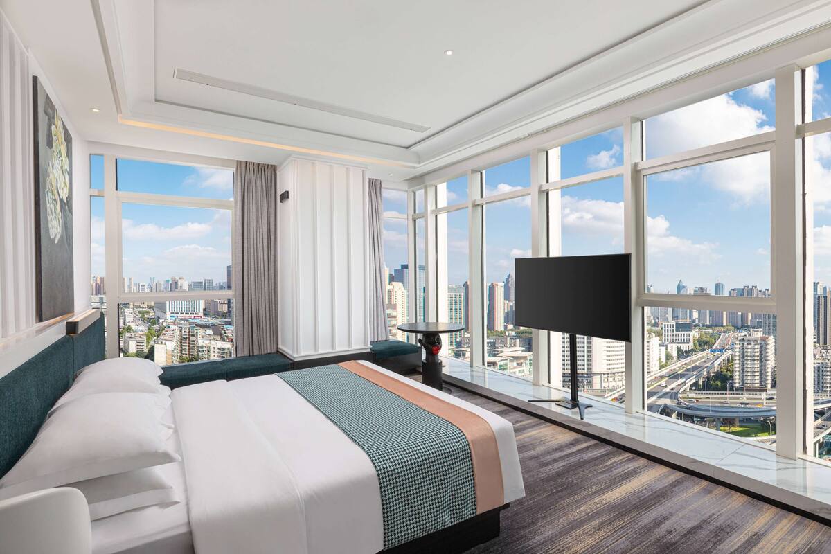 Une chambre d’hôtel moderne avec un grand lit, une télévision et une vue sur la ville.