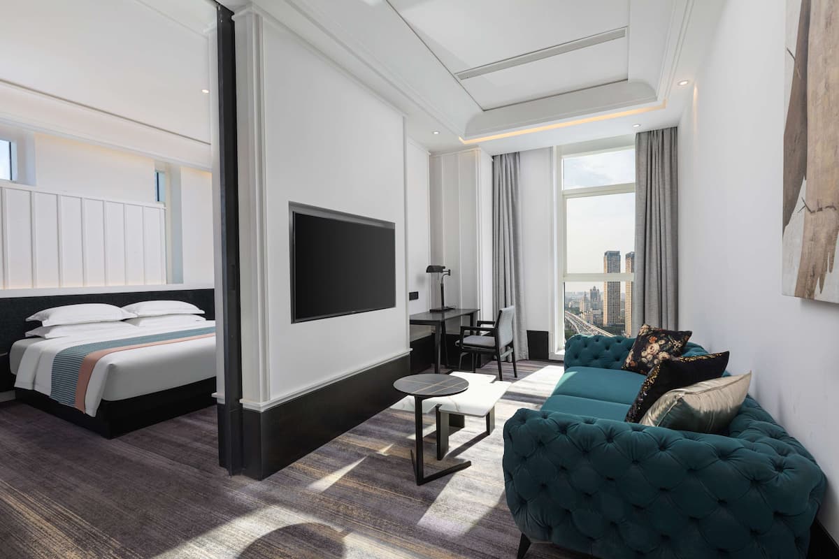 Une chambre d’hôtel moderne équipée d’un lit, d’un canapé, d’une télévision et offrant une vue sur la ville.