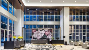 A modern lobby with a reception desk, seating area, and large windows offering views of the cityscape. - Wyndham Garden Wuhan Hankou (Wuhan)