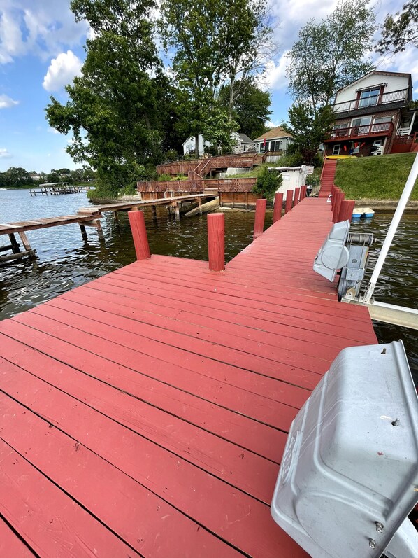 A red wooden dock extending into a body of water with a house and trees in the background. - Waterfront With Relaxing Views (Pasadena)