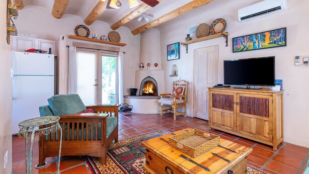 A cozy living room with a fireplace, wooden furniture, a television, and a ceiling fan.