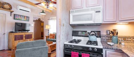 A kitchen with a gas stove, a microwave, and pink towels hanging on the oven door.