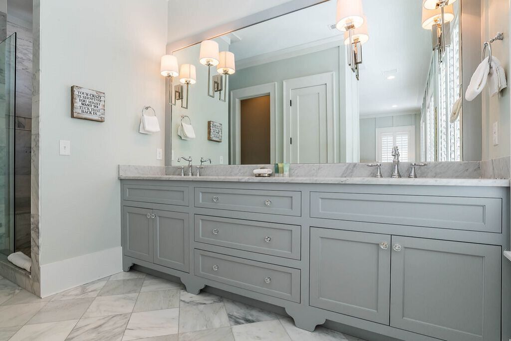 A bathroom with a large vanity, a mirror, and wall-mounted lights.