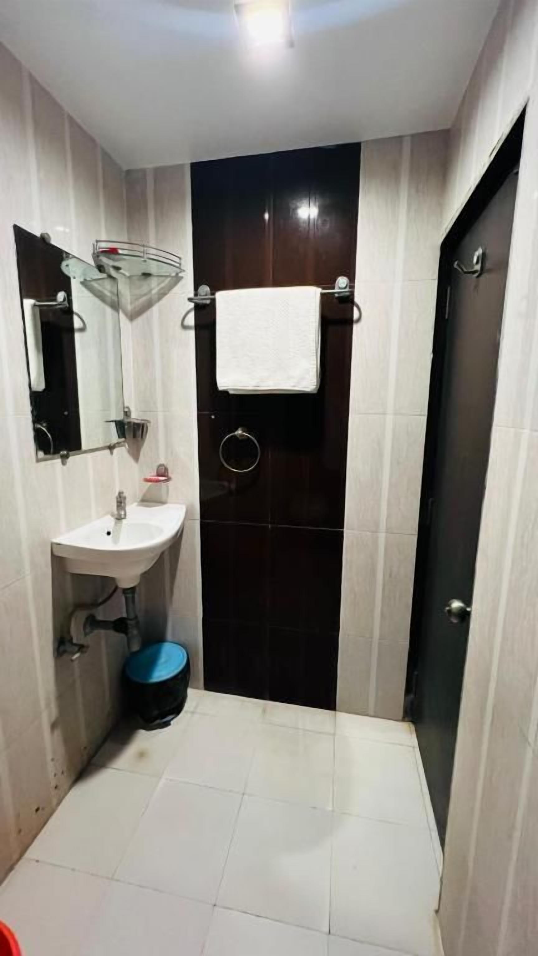 A small bathroom with a sink, mirror, and dark-colored door.