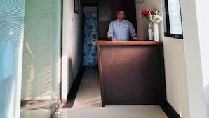 A reception desk with a sign reading 'Farmhouse Residency' and a person standing behind it. - Farmhouse Residency (Vasai)