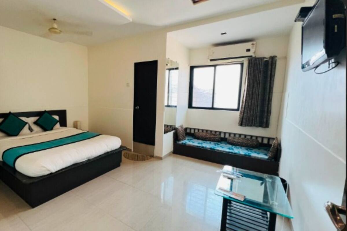 A hotel room with a bed, a glass table, a sofa, and a TV.