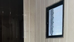 A bathroom with a toilet, a window, and a shower. - Farmhouse Residency (Vasai)