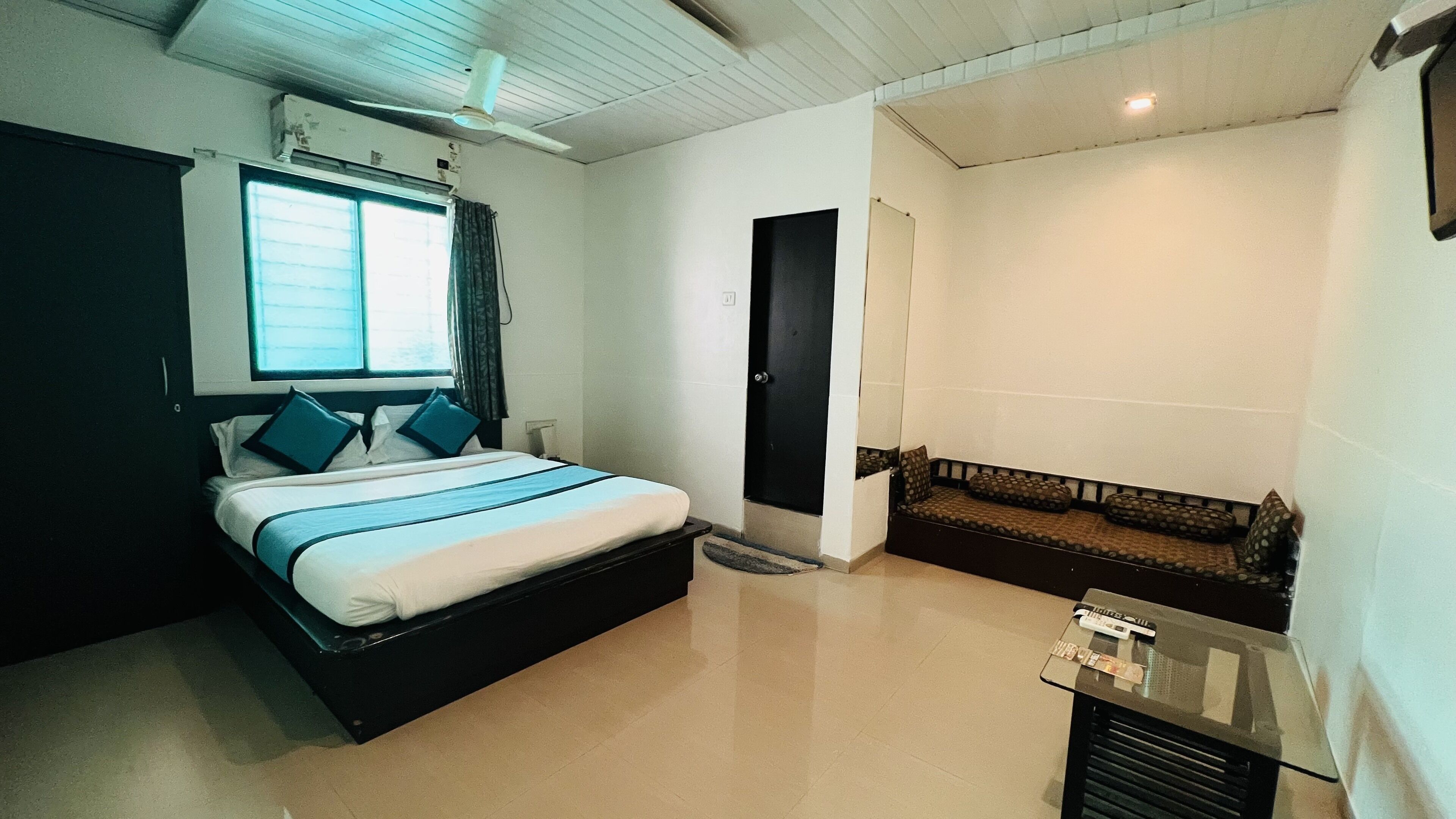 A bedroom with a bed, a window, a door, and a seating area.