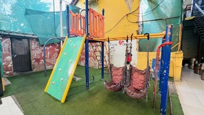 A children's play area with a slide, climbing structures, and hanging swings. - Farmhouse Residency (Vasai)