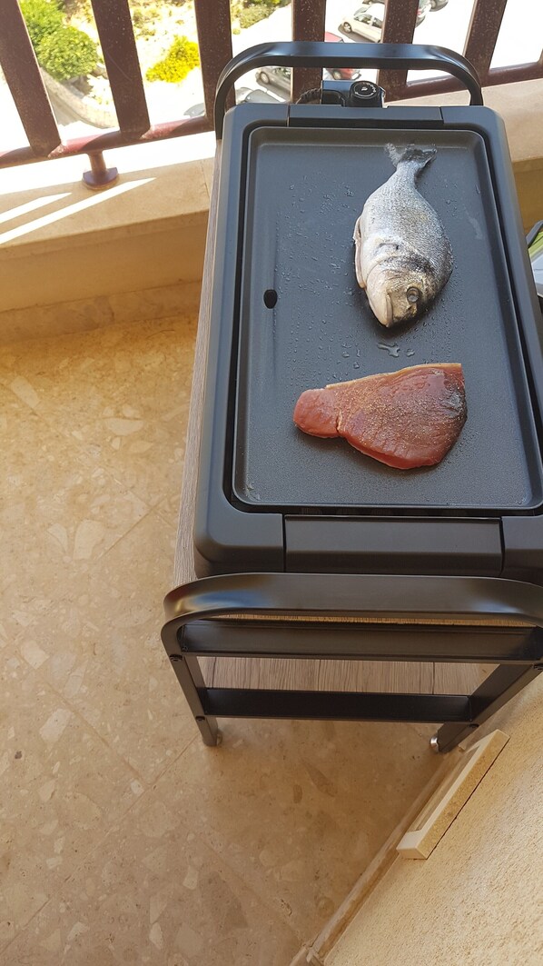 A portable grill with a fish and a piece of meat on it.