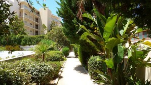 Un sentier bordé d’une végétation luxuriante et, au fond, un bâtiment doté de balcons.