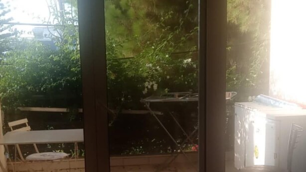 Een kamer met een schuifdeur die uitkomt op een buitengebied met een tafel en stoelen.