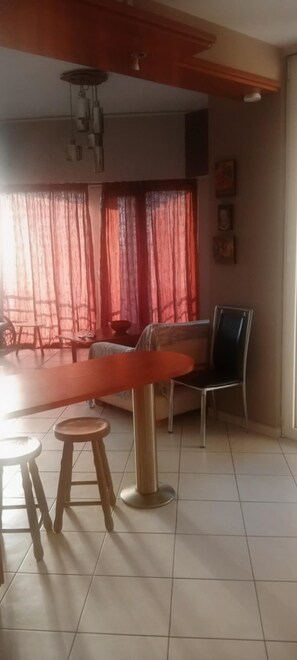 Un coin repas comprenant une table, deux tabourets, un canapé et une chaise.