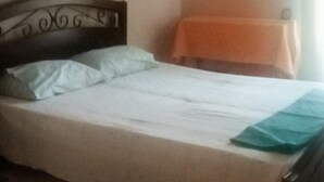 Een slaapkamer met een bed, een nachtkastje, een wandairconditioner en een lijst met een afbeelding.