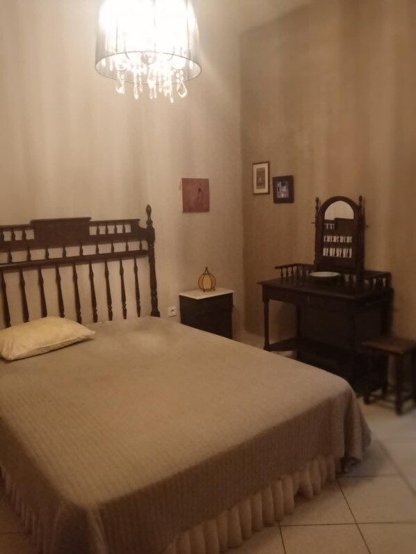 A bedroom with a wooden bed, a nightstand, a dresser, a mirror, and a chandelier.