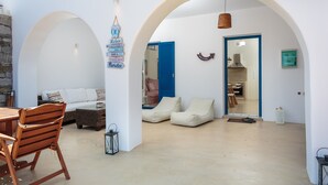 A spacious living area with a wooden table, cushioned seating, and a stone wall.
