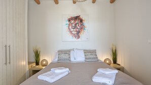 A bedroom with a large bed, two bedside tables with lamps, a wall-mounted artwork, and a wardrobe.
