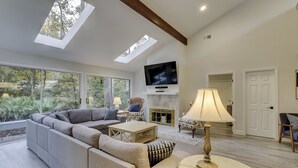 Una sala de estar moderna con un sofá modular, un televisor en la pared y una chimenea.