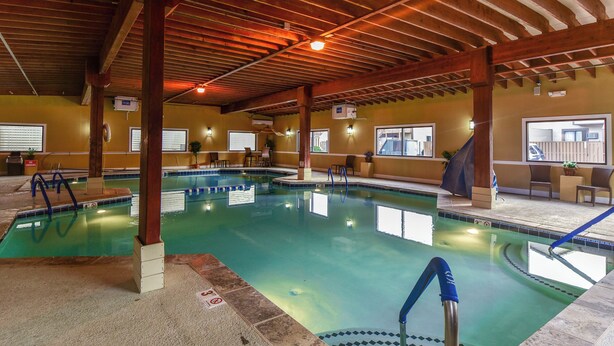 Una piscina interior con agua cristalina, vigas de madera en el techo y una silla para socorrista.