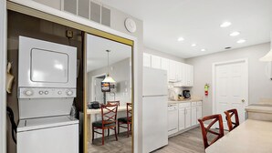Una cocina moderna con electrodomésticos blancos, sillas de madera y una mesa de comedor.