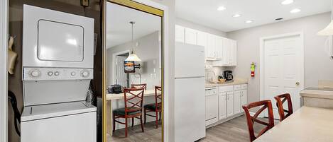 A modern kitchen with white appliances, wooden chairs, and a dining table.
