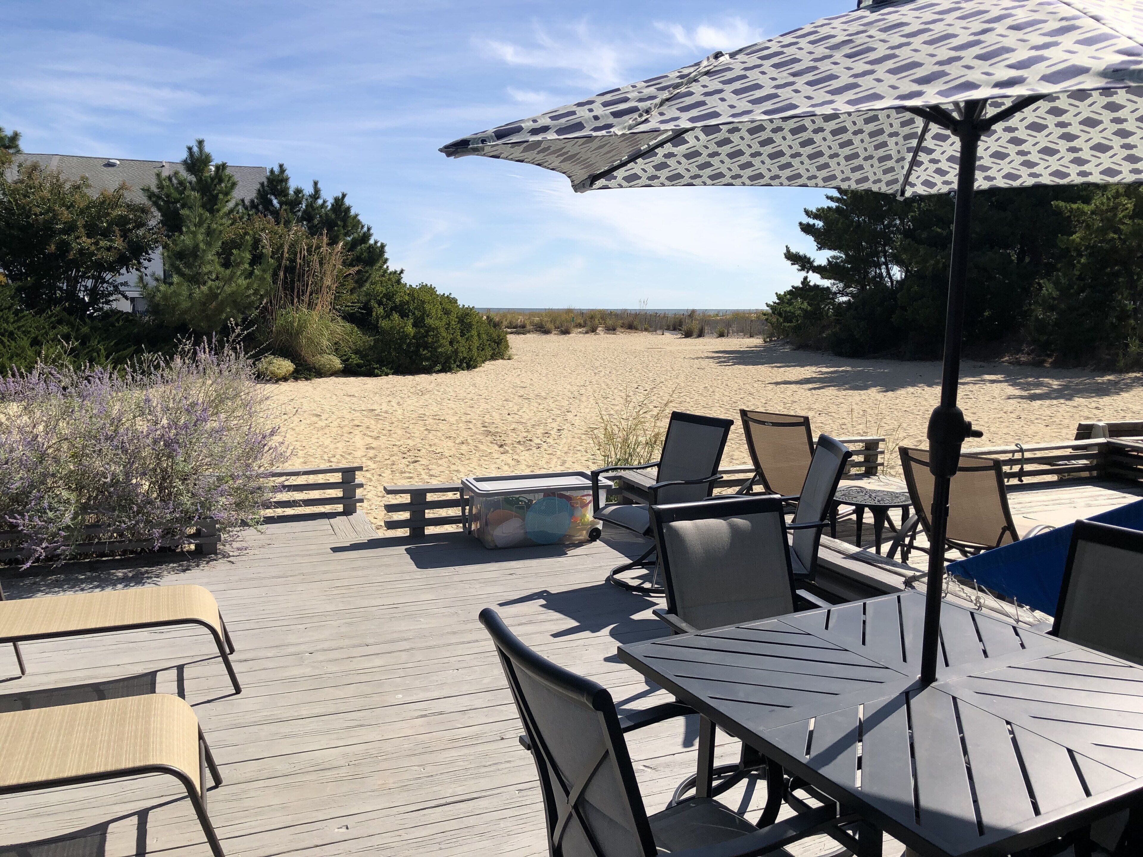 A beachside patio with outdoor seating and a large umbrella.