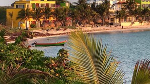 Uma região costeira com edifícios coloridos, uma praia e um barco na água.