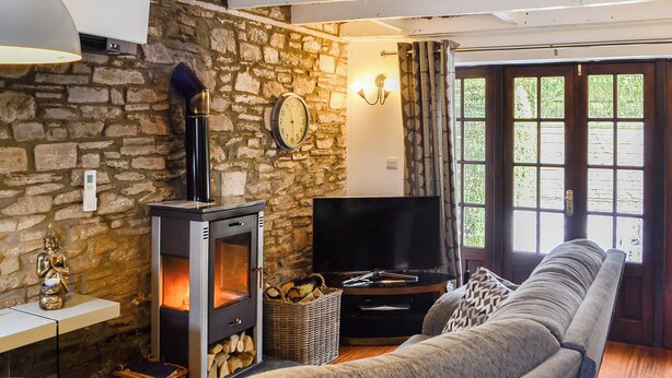 A stone-walled living room with a wood-burning stove, a television, and a sofa. - 1 bedroom accommodation in Merthyr Cynog, near Brecon (Merthyr Cynog, near Brecon)
