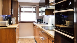 A modern kitchen with wooden cabinets, a stainless steel sink, a built-in oven, and a microwave. - 1 bedroom accommodation in Merthyr Cynog, near Brecon (Merthyr Cynog, near Brecon)