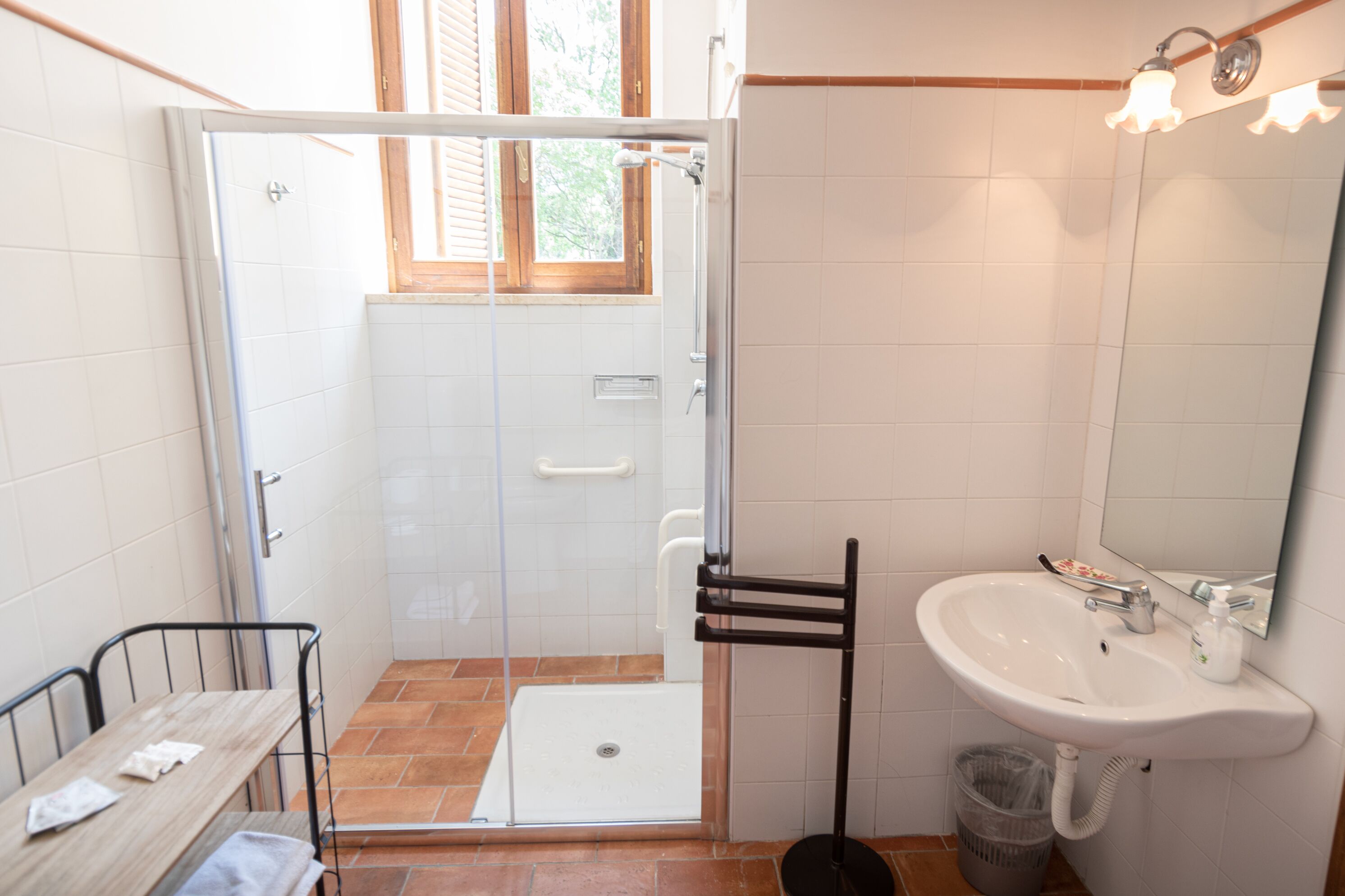 Un bagno con doccia, lavandino e finestra.
