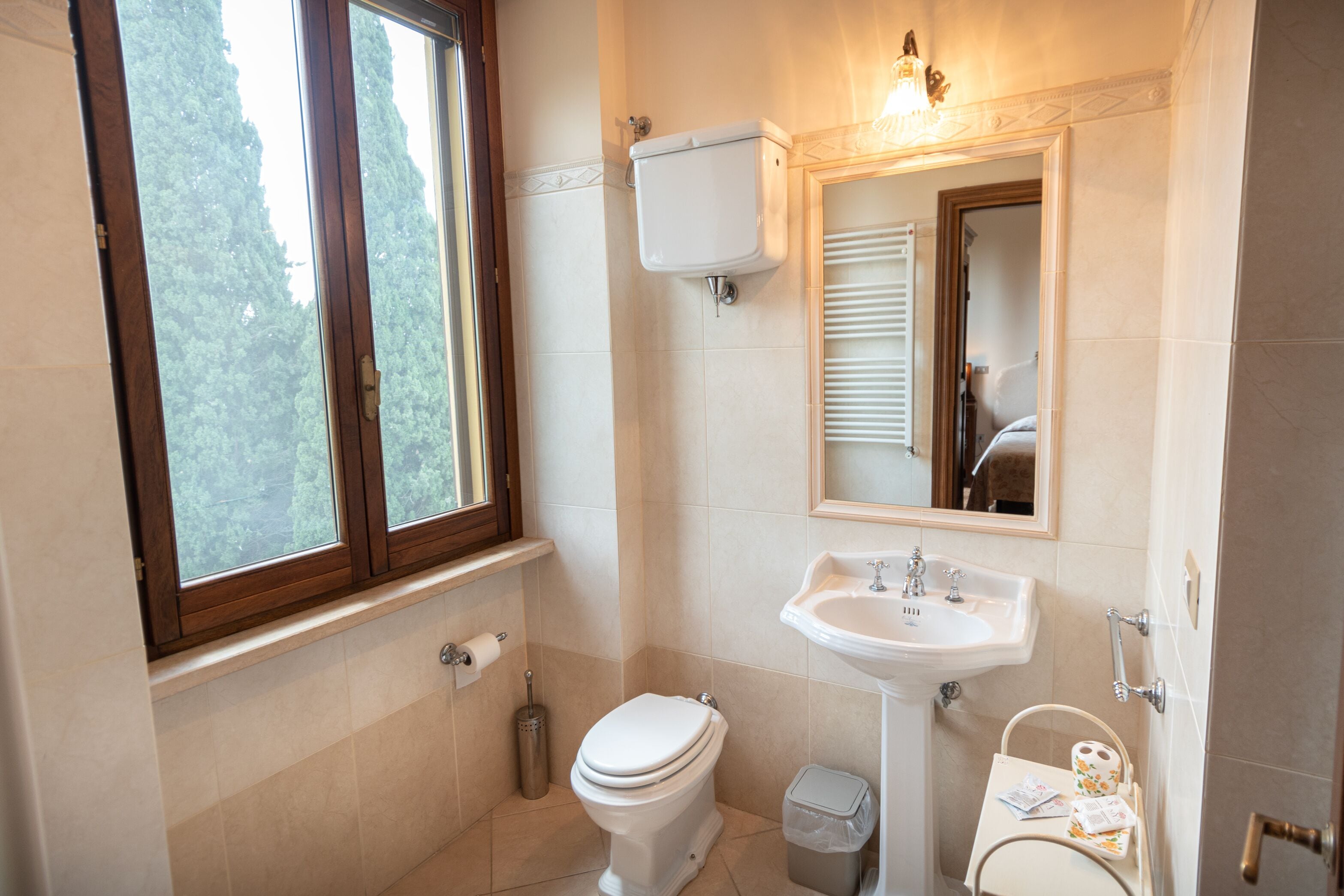 A bathroom with a toilet, sink, and window.