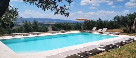 Una piscina al aire libre de temporada, sombrillas