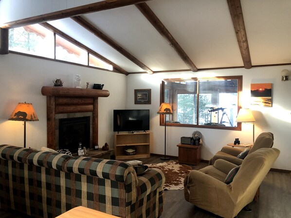 A cozy living room with a fireplace, wooden beams, a television, and comfortable seating. - Spectacular waterfront setting, comfy cabin (Hazelhurst)