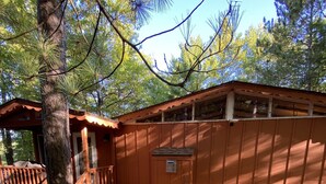 A cabin with a wooden deck, a covered porch, and a stone pathway. - Spectacular waterfront setting, comfy cabin (Hazelhurst)
