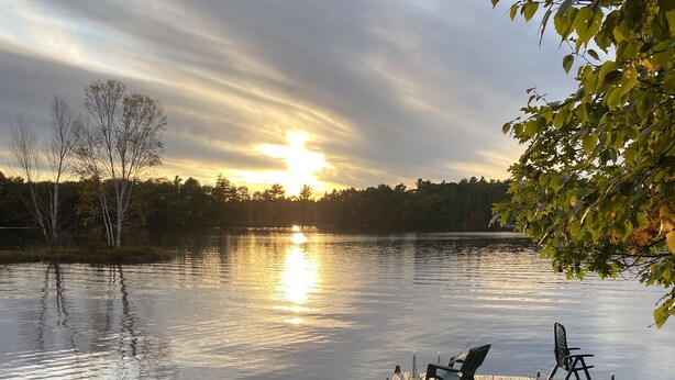 A wooden dock extending into calm water with a sunset in the background. - Spectacular waterfront setting, comfy cabin (Hazelhurst)
