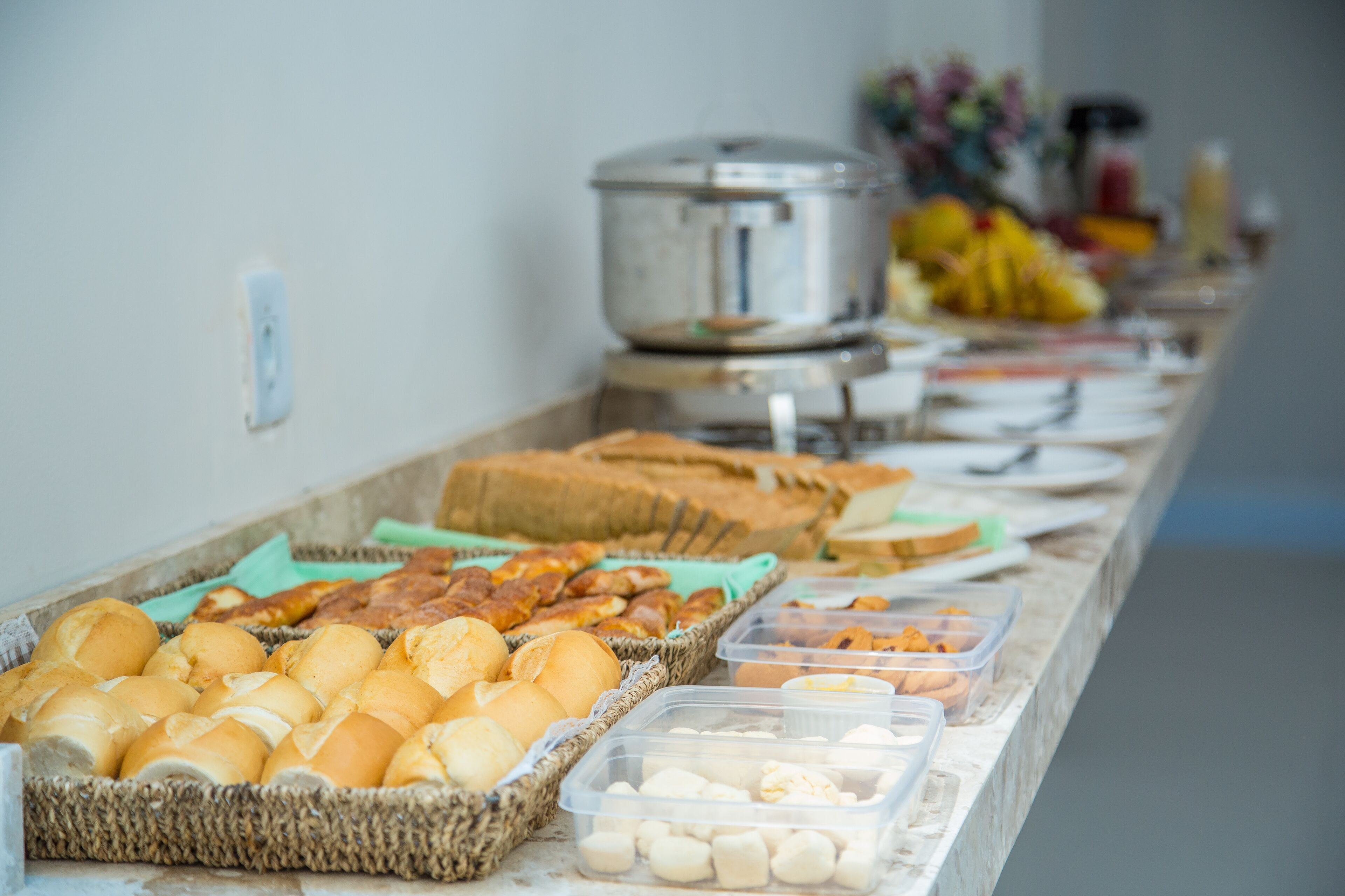 Un bufé con diferentes opciones de comida, incluyendo pan, bollería y recipientes con alimentos.