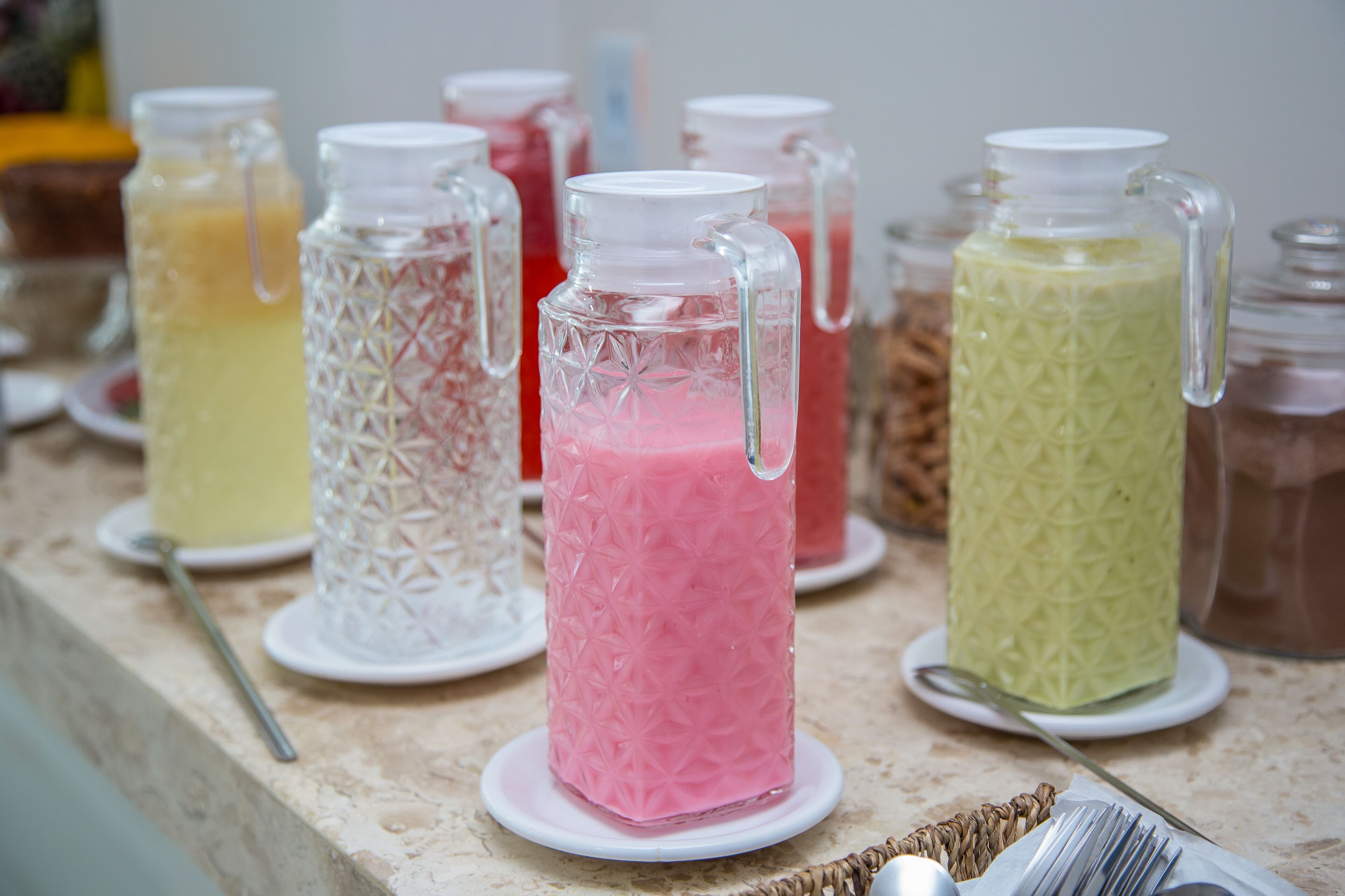 A variety of colorful beverages in glass containers on a countertop.