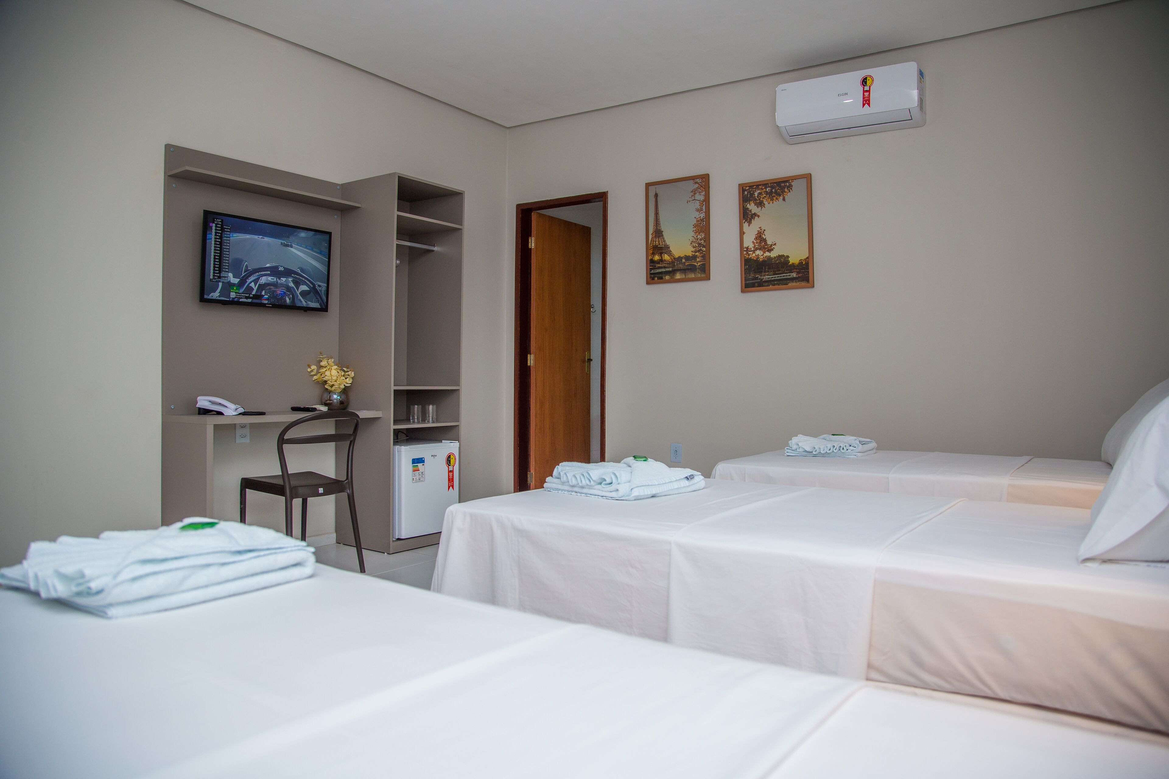Ein Hotelzimmer mit zwei Betten, einem Schreibtisch, einem Stuhl, einem Fernseher und einem Kleiderschrank.