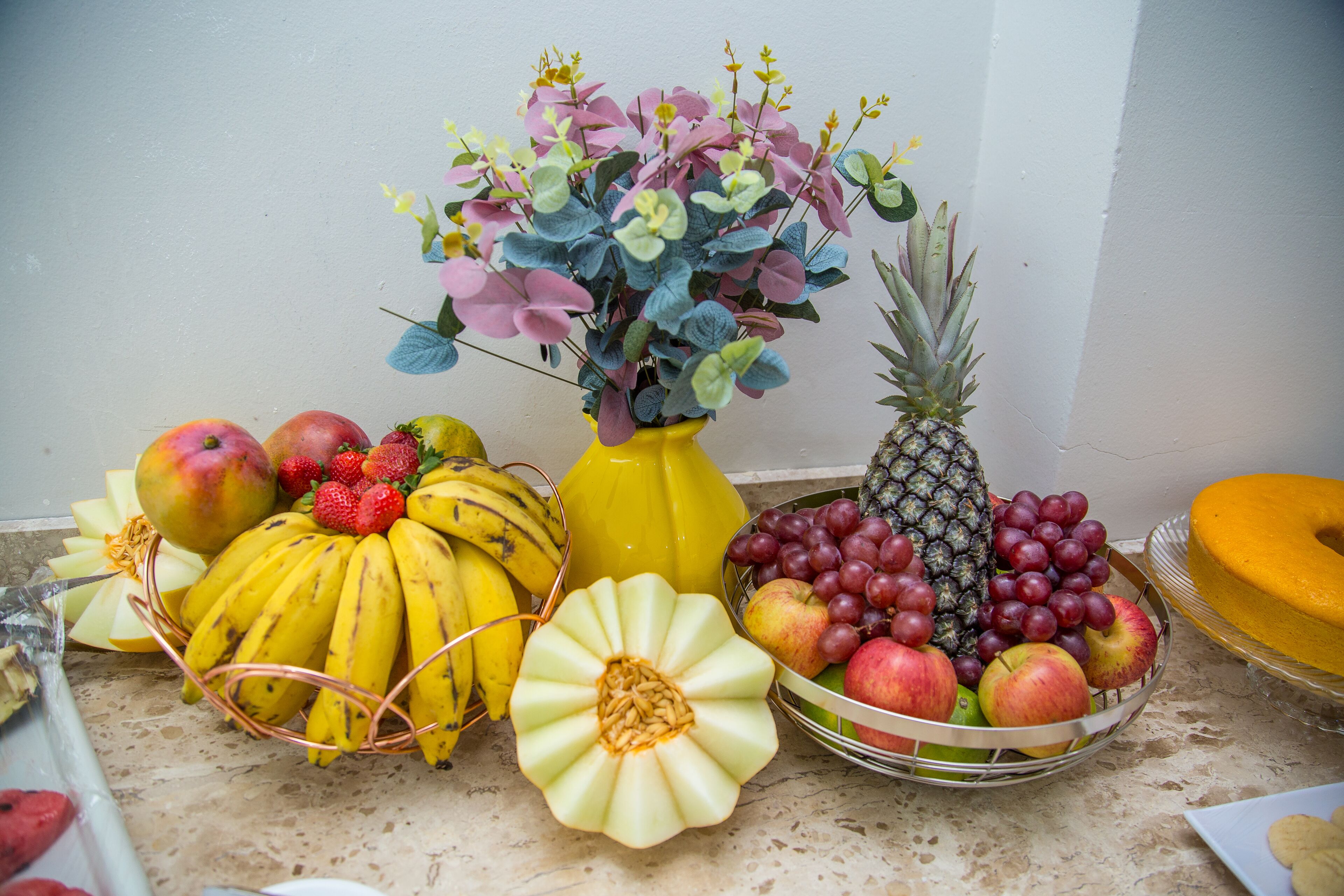 Une composition de fruits comprenant des bananes, des pommes, des raisins et un ananas, disposée sur un comptoir.