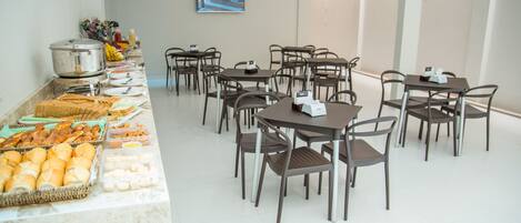 A buffet setup with various food items and a seating area with tables and chairs.