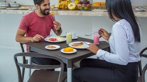 Una mesa de comedor con platos de comida y bebidas, rodeada de sillas.